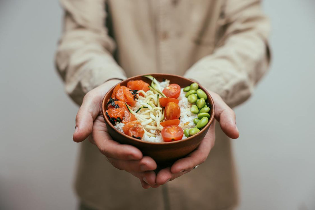 A person holding a bowl of rice with chopped tomatoes