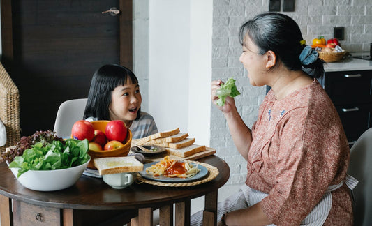 A young girl eating salad with her grandmother 